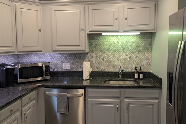 Fully stocked kitchen with granite countertops and stainless-steel appliances. Water and ice machine on fridge.