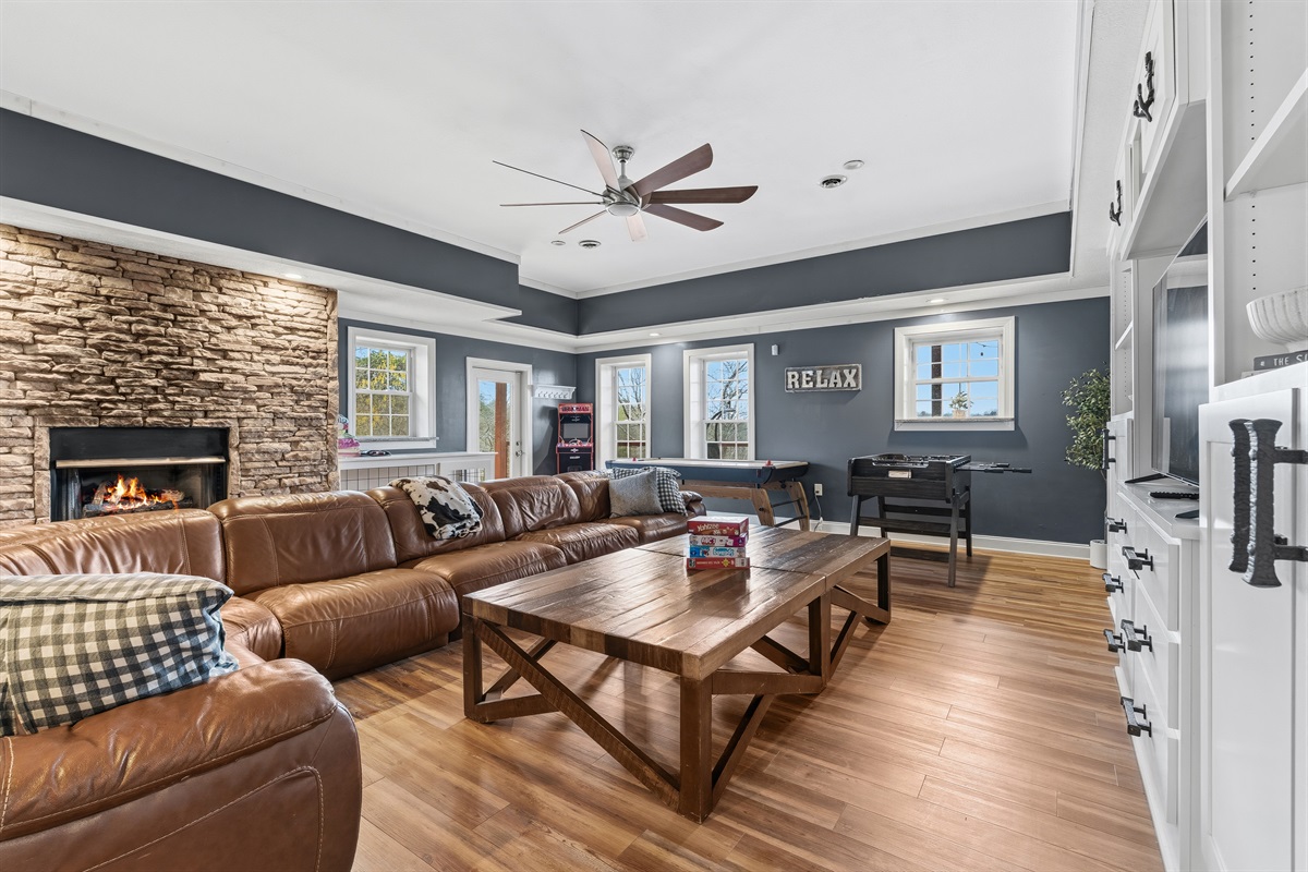 Huge basement and gathering space with massive couch, fireplace and air hockey, arcade and foosball