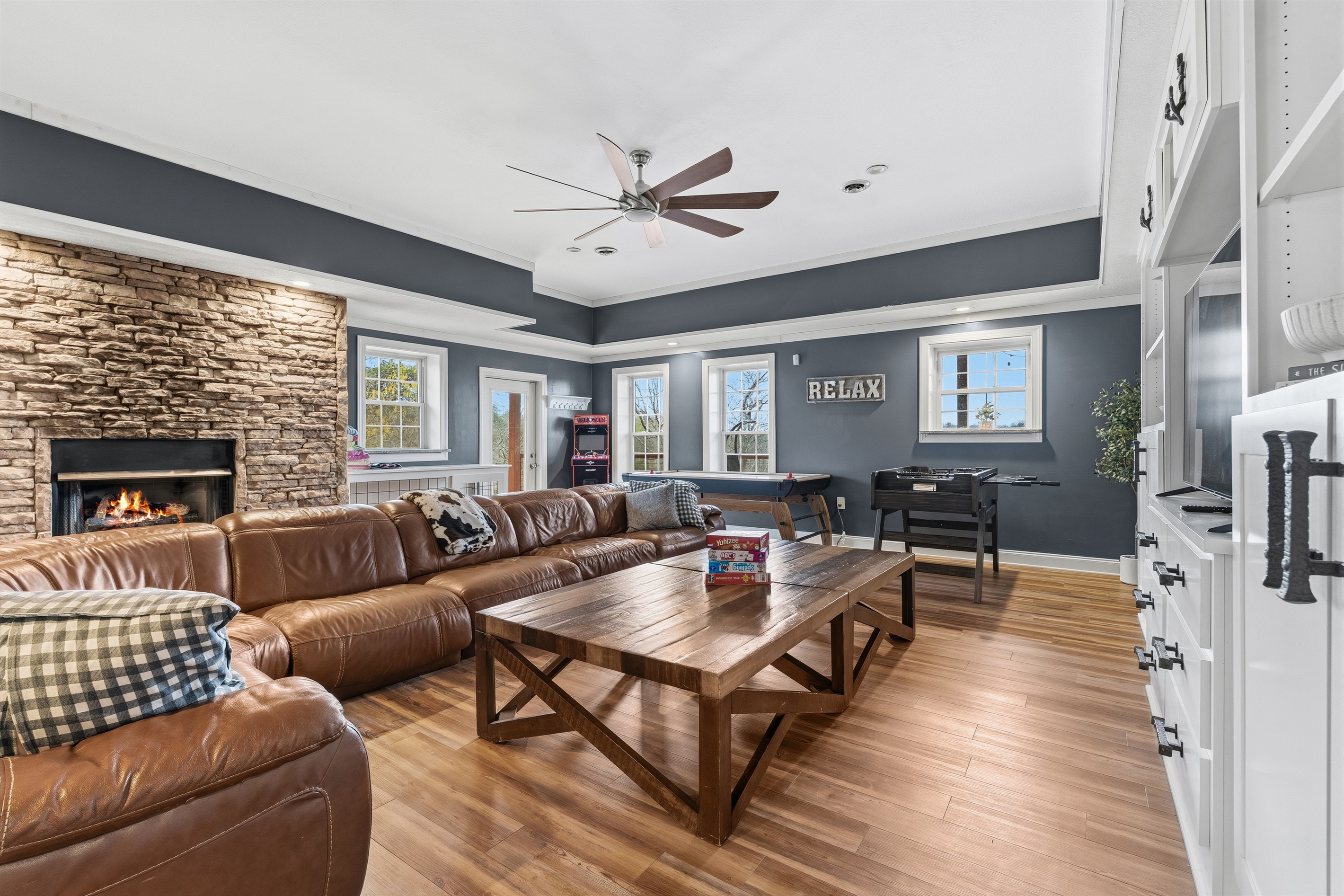 Huge basement and gathering space with massive couch, fireplace and air hockey, arcade and foosball