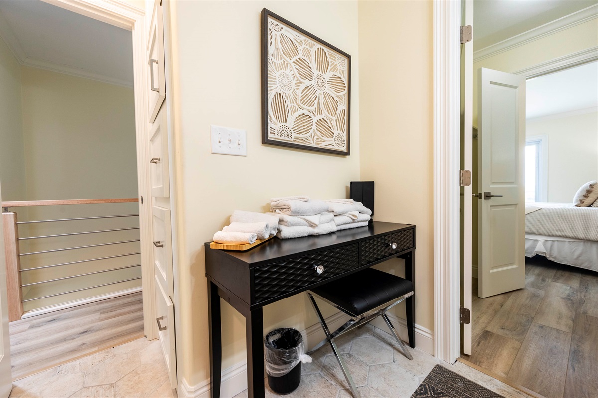 Cozy hallway nook with modern black desk, fresh towels, and stylish decor.