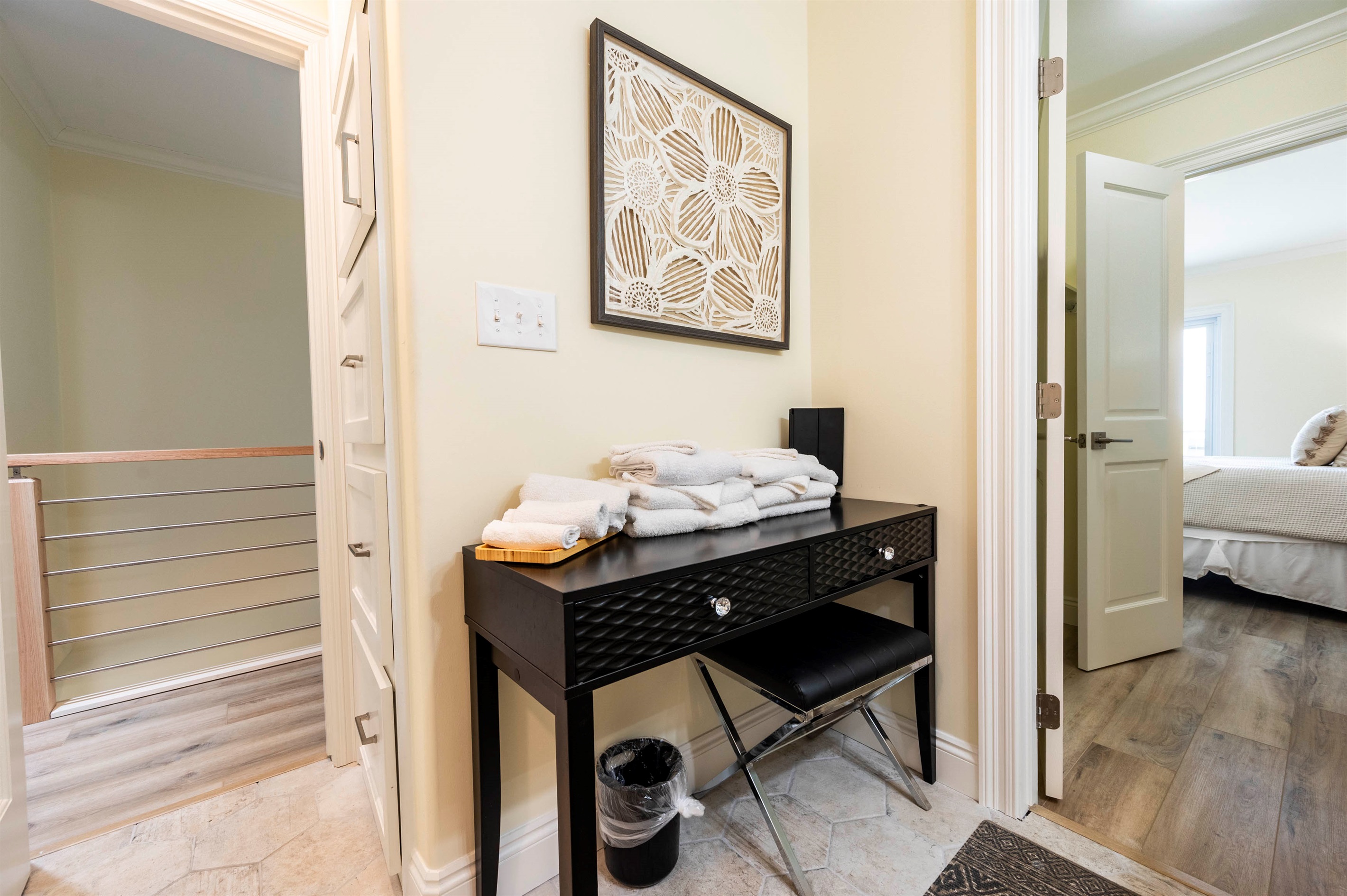 Cozy hallway nook with modern black desk, fresh towels, and stylish decor.