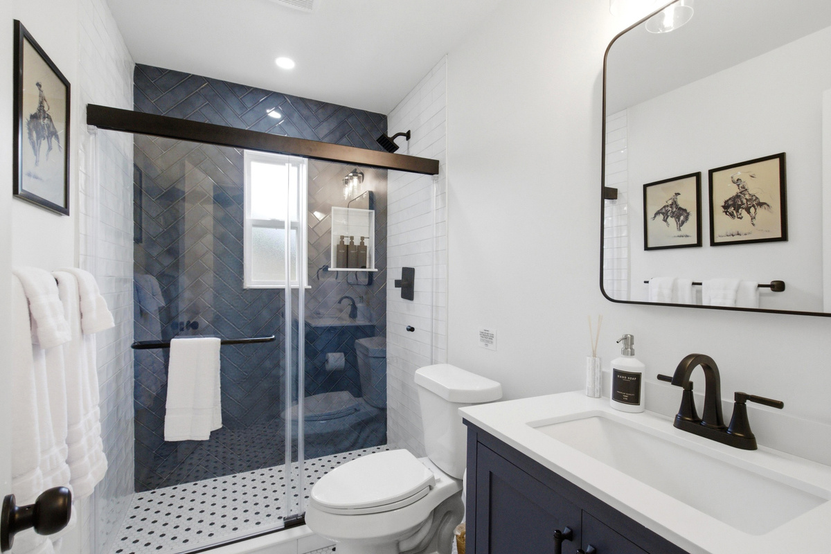 Modern Bathroom with spacious Standing Shower, Single Vanity, and stylish gallery wall. Stocked with essentials by Ginger Lily Farms, fresh towels, Hairdryer, and Hot Water.