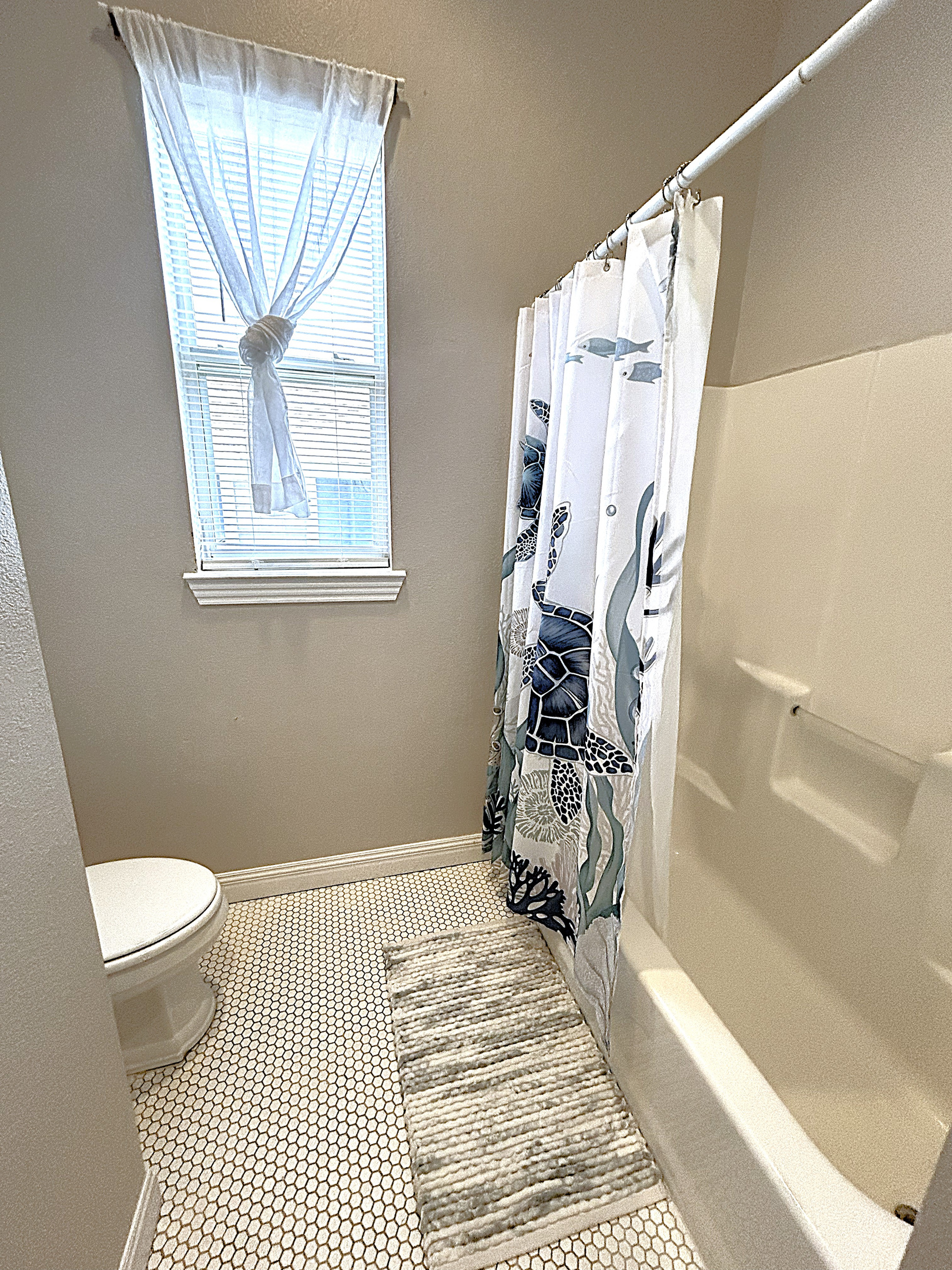 Sparkling clean bathroom with tub/shower combo, beadboard accents, and coastal-inspired decor. This well-appointed shared bathroom serves the bunk room and common areas with style and function