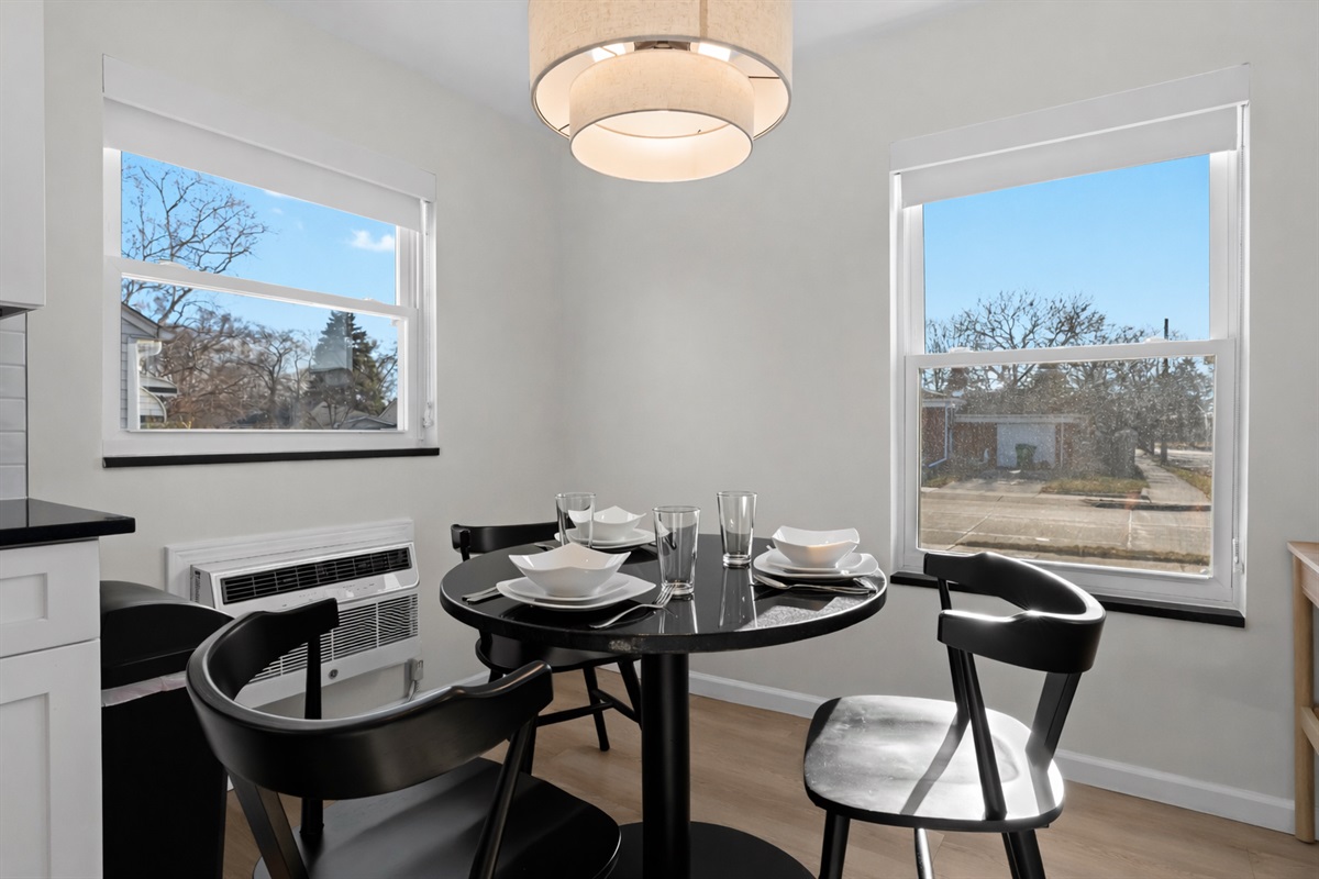 Sun-filled dining nook with modern table setting, stylish chairs, and soft pendant lighting—an inviting spot for meals, coffee, or conversation.