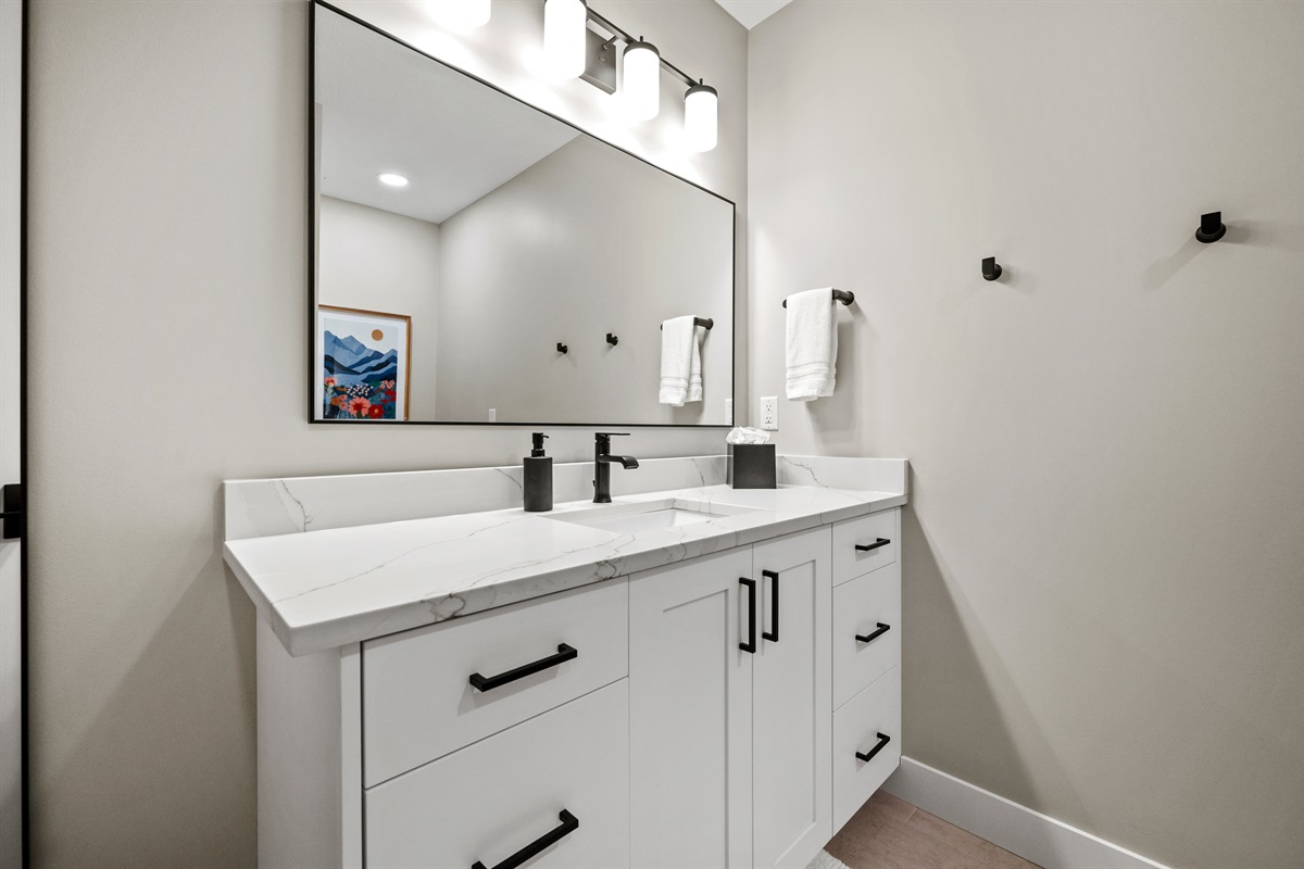 This bathroom also offers a spacious cabinet with a single sink and a large mirror.
