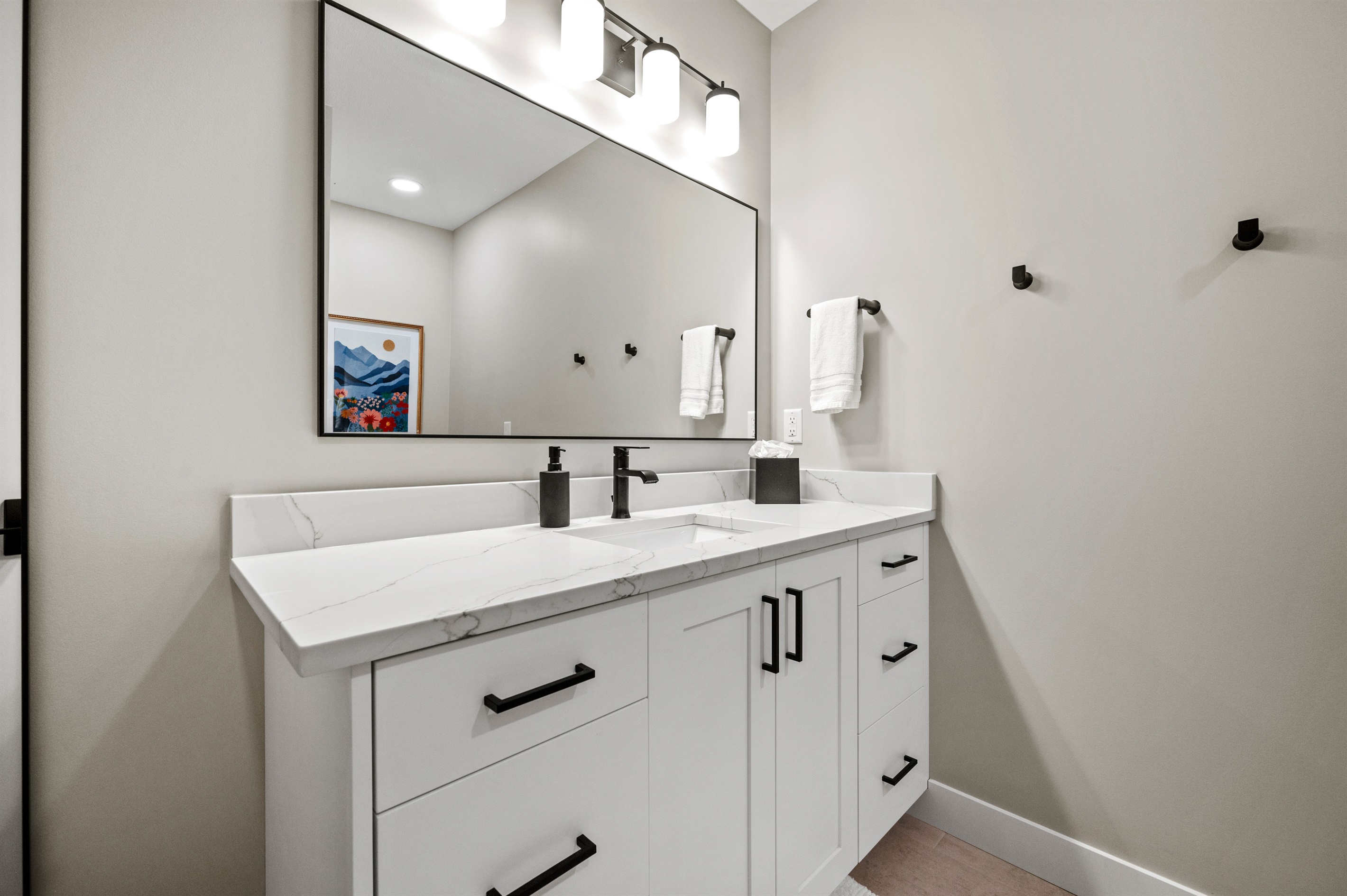 This bathroom also offers a spacious cabinet with a single sink and a large mirror.