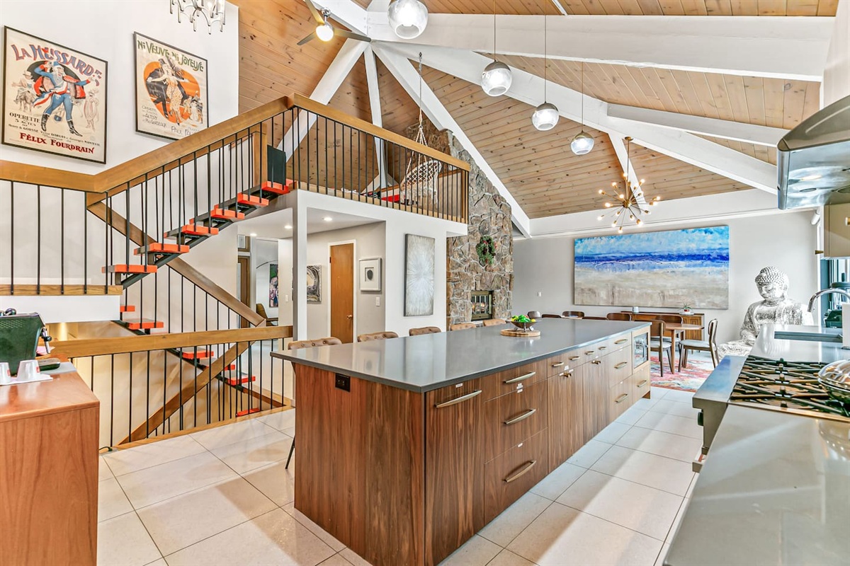 The kitchen is fully equipped with modern appliances, a Mid-Century Modern interior design, a large fridge, freezer, and ample storage. It boasts a spacious layout and a 16 ft island table, with convenient access to the outdoor area.
