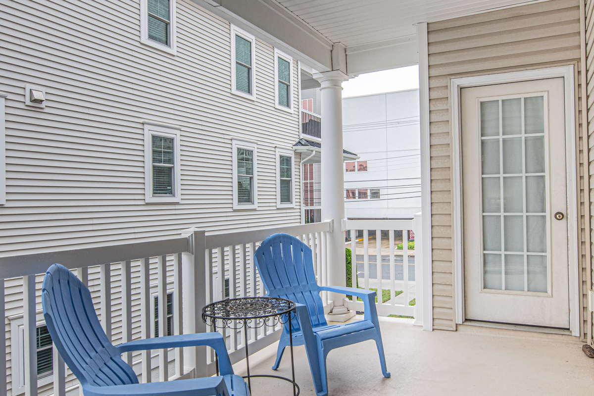 Covered Balcony with Blue Adirondack Chairs and Accent Table