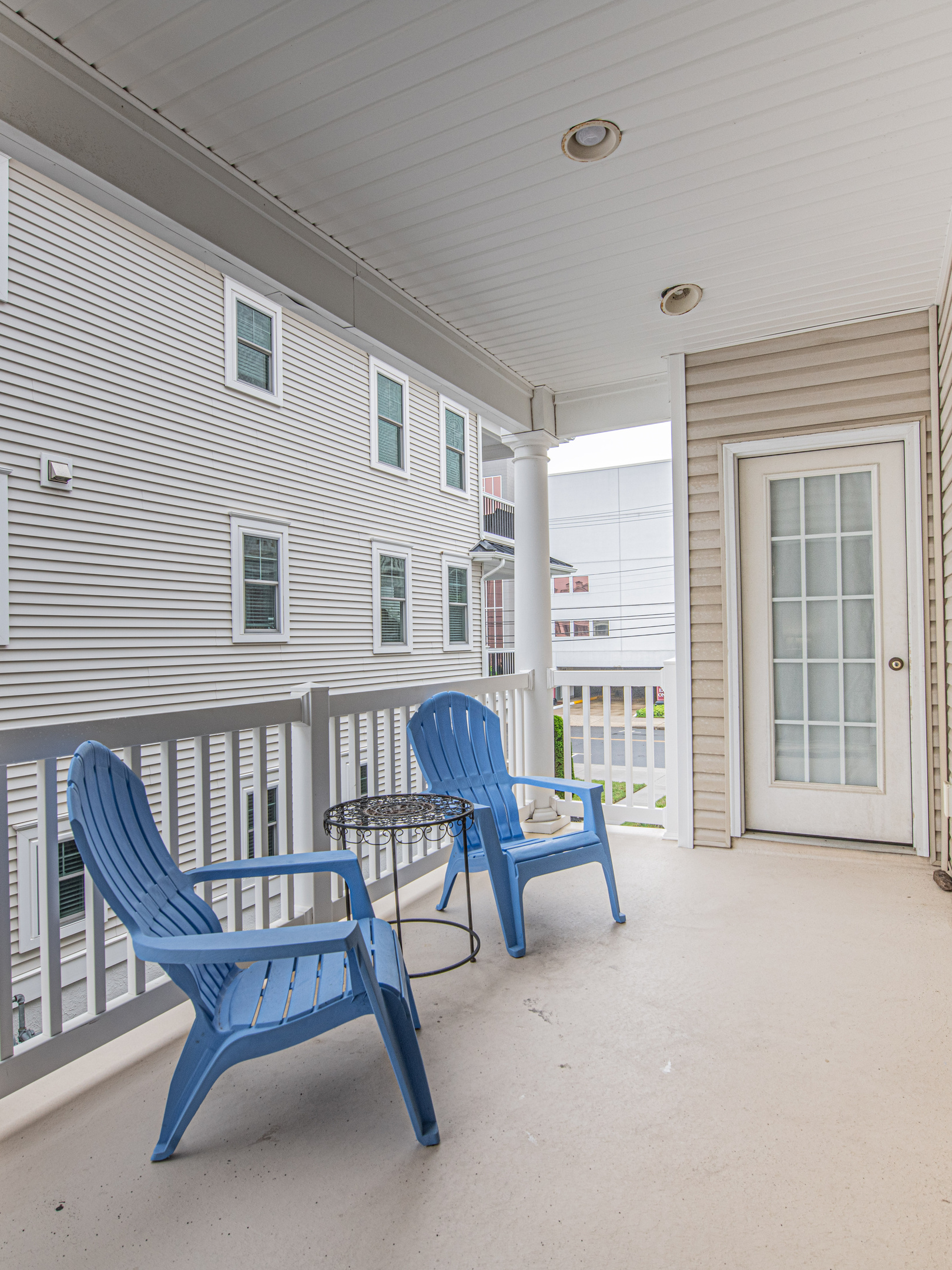 Covered Balcony with Blue Adirondack Chairs and Accent Table
