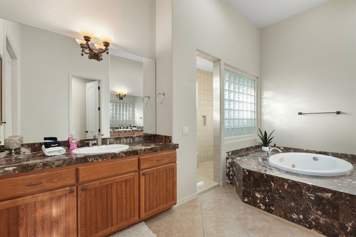 Elegant en suite bathroom featuring a soaking tub and glass block accents.
