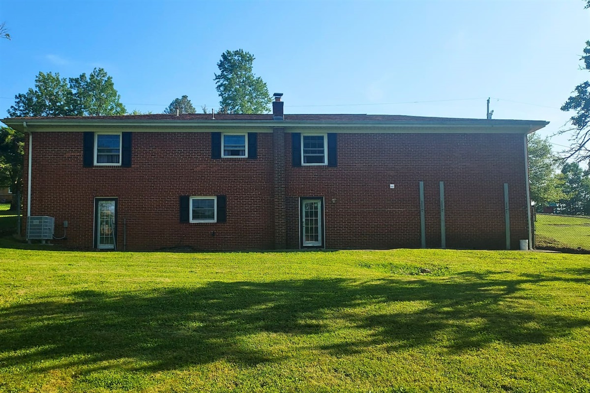  The back of this brick ranch has a stately, welcoming feel, with a cozy little patio nestled against the house and a view over the fully fenced, chain-link yard—perfect for peaceful mornings or playful afternoons.