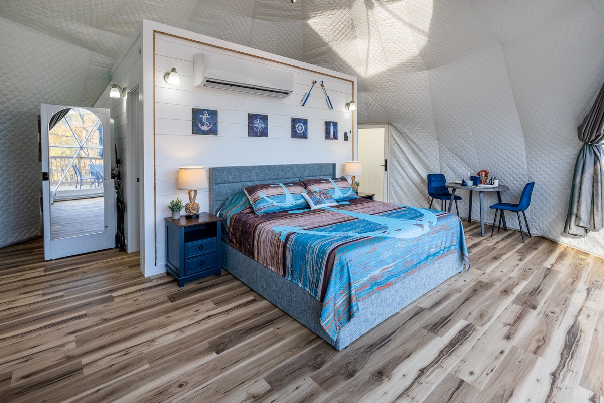 Bright, spacious king bedroom with cozy lighting, nautical décor, and a dining area tucked perfectly into the dome’s open layout