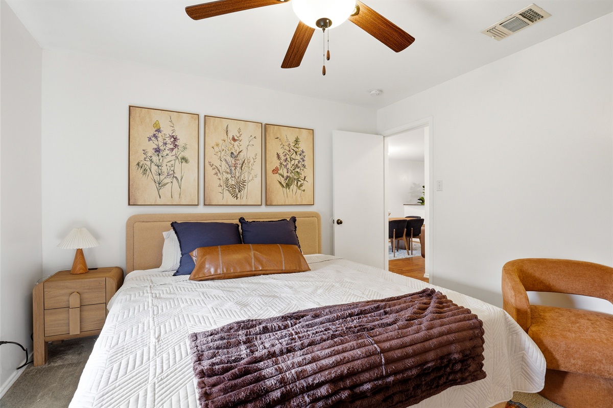 Guest bedroom with wall-mounted Smart TV, ceiling fan, lock on the door for privacy, and full closet storage. Clean, comfortable setup ideal for families, work trips, or Lackland AFB military stays.