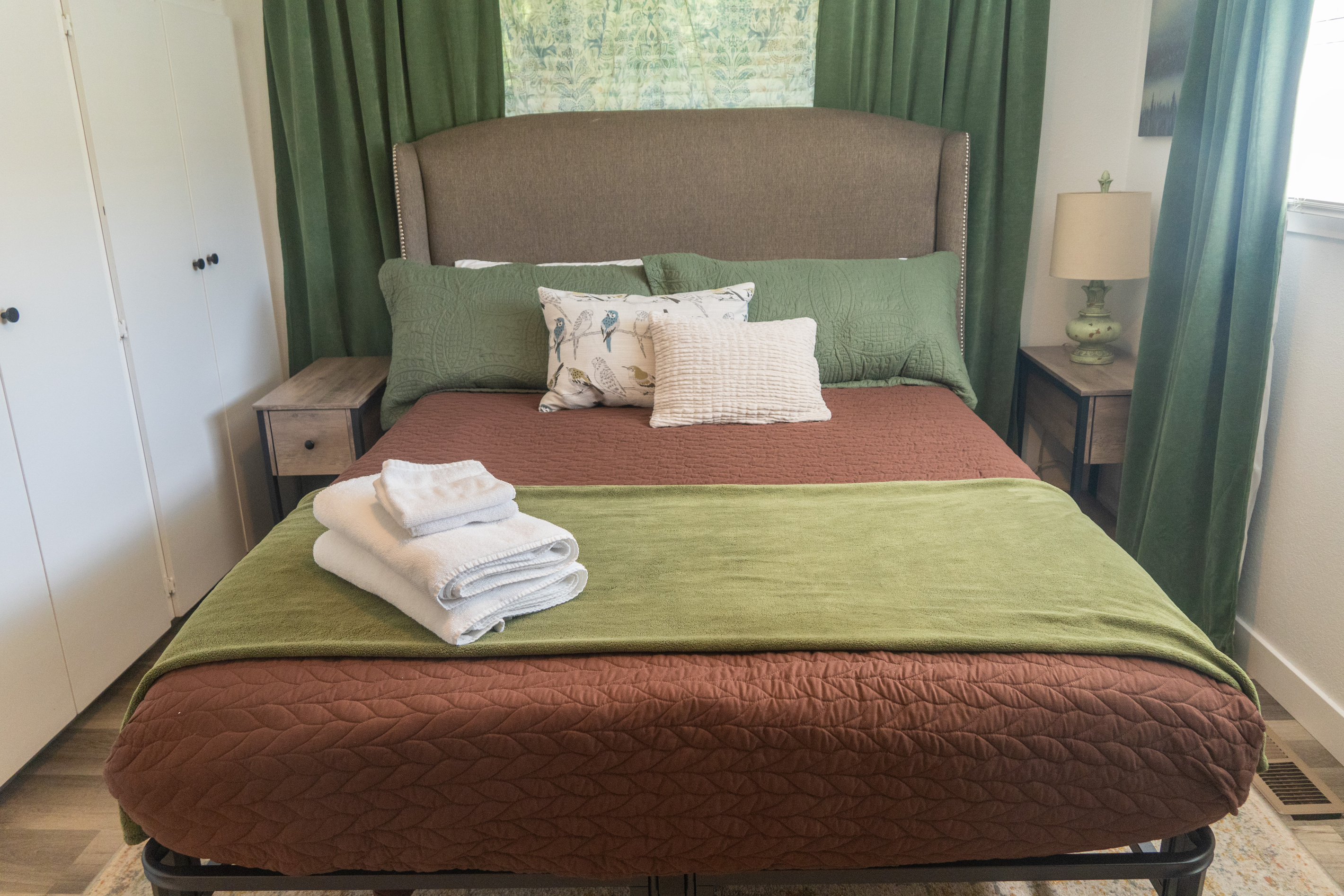 A serene queen bedroom featuring a TV and a calming nature-inspired theme with birds, blending soft patterns and layered elements for a restful retreat.