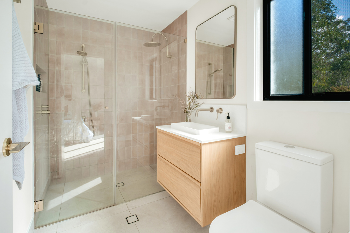 A bright, modern bathroom featuring a spacious walk-in shower with both rainfall and handheld shower options.