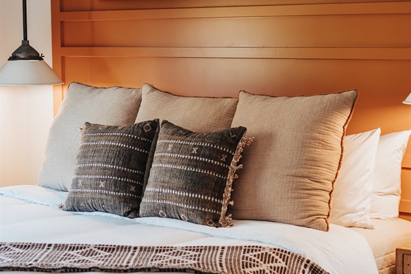 Comphy linens layered with handcrafted Western pillows at the Bedroom #2 bedside.