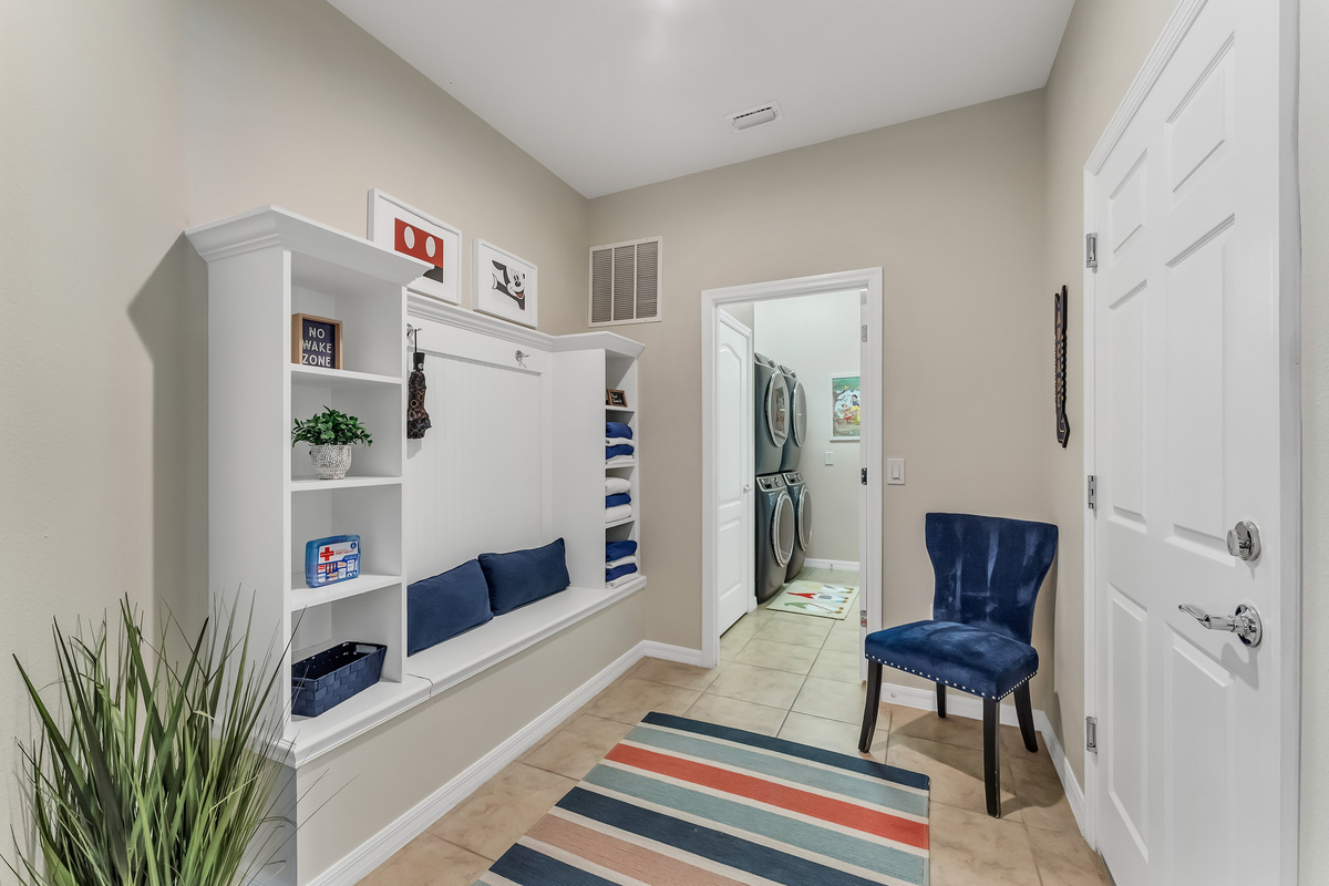 Hallway to laundry room with pool towels, first aid kit, and umbrella