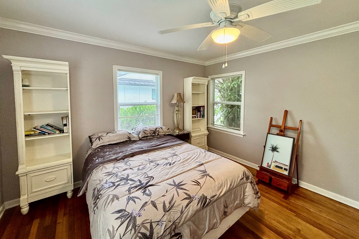 The second bedroom features a queen-zied bed and a stylish painter's floor stand.