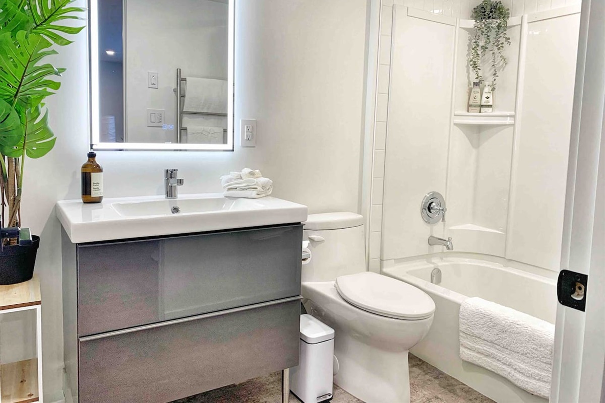Main bathroom with modern vanity, illuminated mirror, and clean, minimalist finishes.