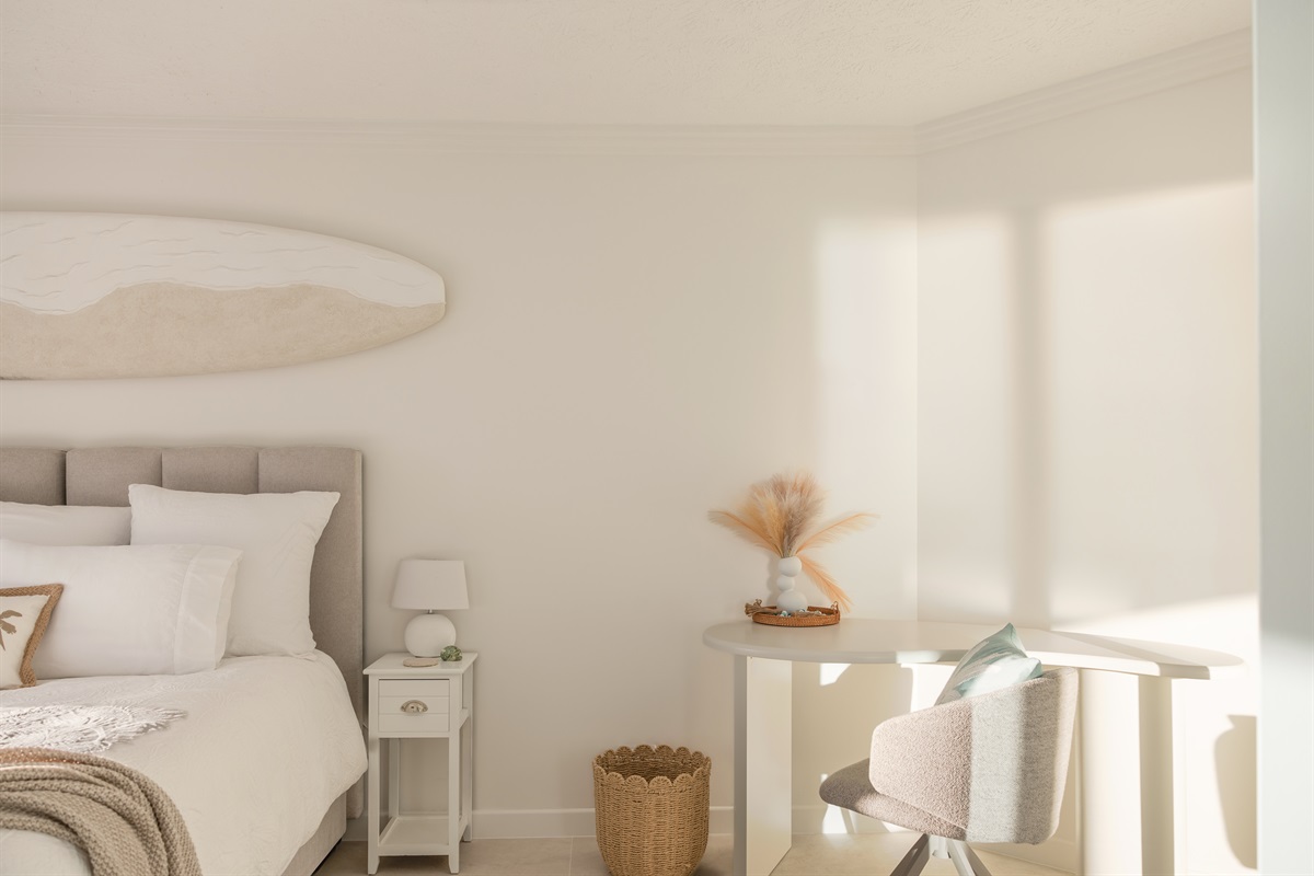 Soft coastal bedroom with workspace and luxury bedding.