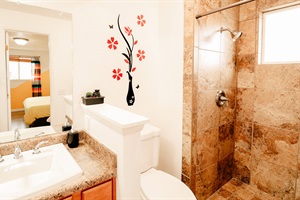 A pristine toilet enhances the tranquil charm of a wall decorated with delicate floral patterns, gently mirrored to evoke nature’s serenity. More than just a space, it’s a retreat for relaxation and self-care.
