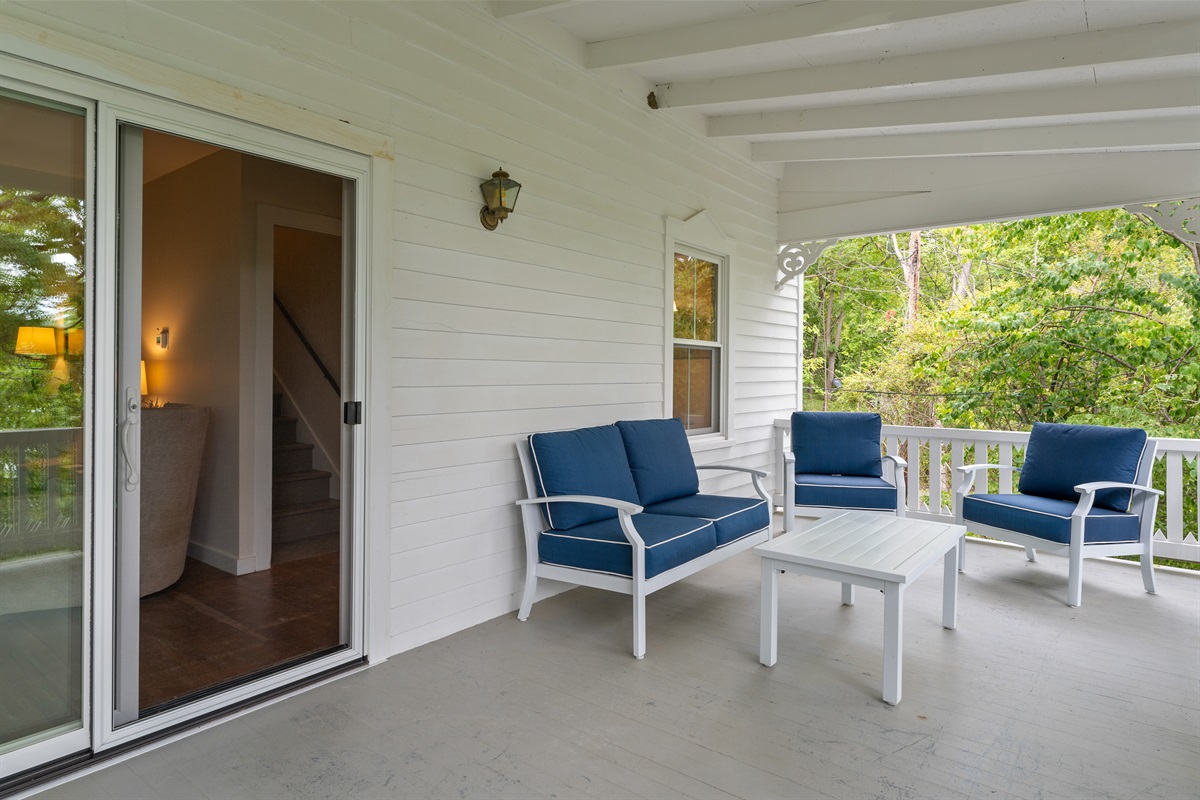 Charming covered porch surrounded by trees, perfect for relaxing with morning coffee or outdoor dining.