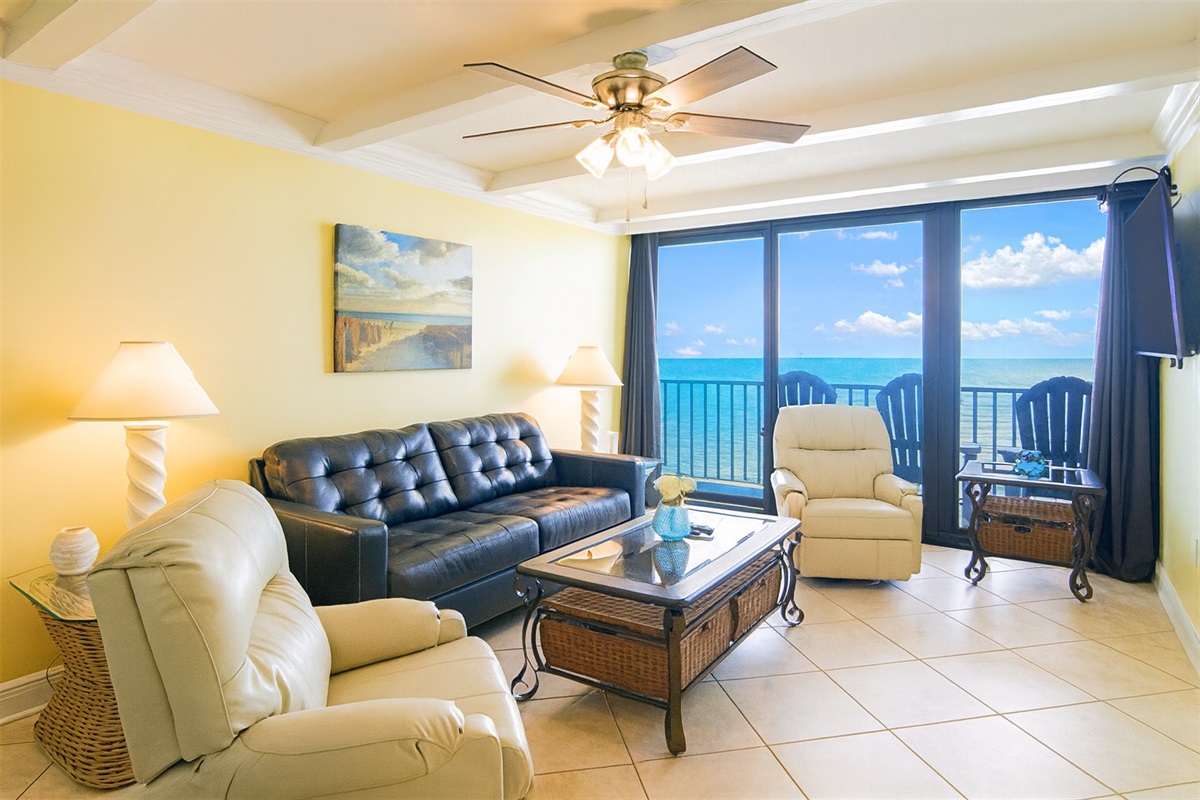 Living Room with A Great View. It Has A Queen Size Leather Sleeper Sofa, 2 Swivel/Rocker Recliners, 3 End Tables, A Coffee Table, A 58" Wall Mounted Smart TV And Balcony Access