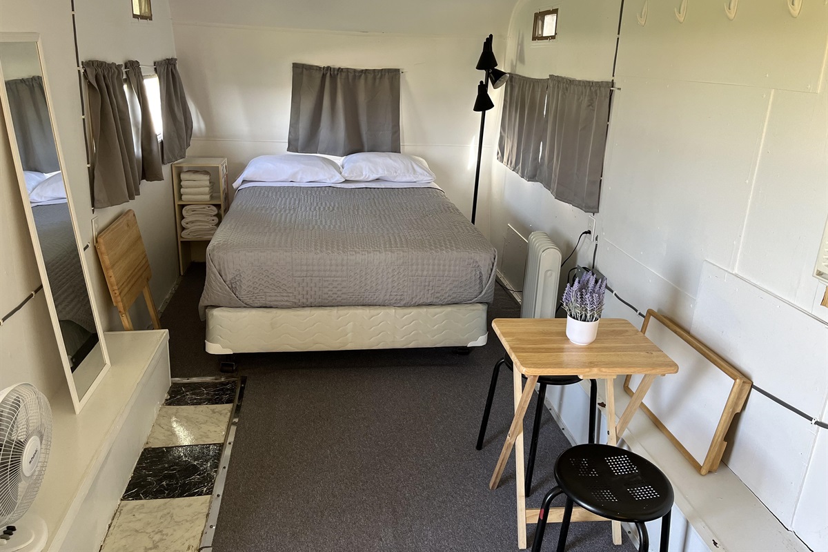 A full size bed with fresh linens and pillows make your nights restful. Two tray tables and two stools are available for dining or work and can be stored to to the side to make more living area when needed.
