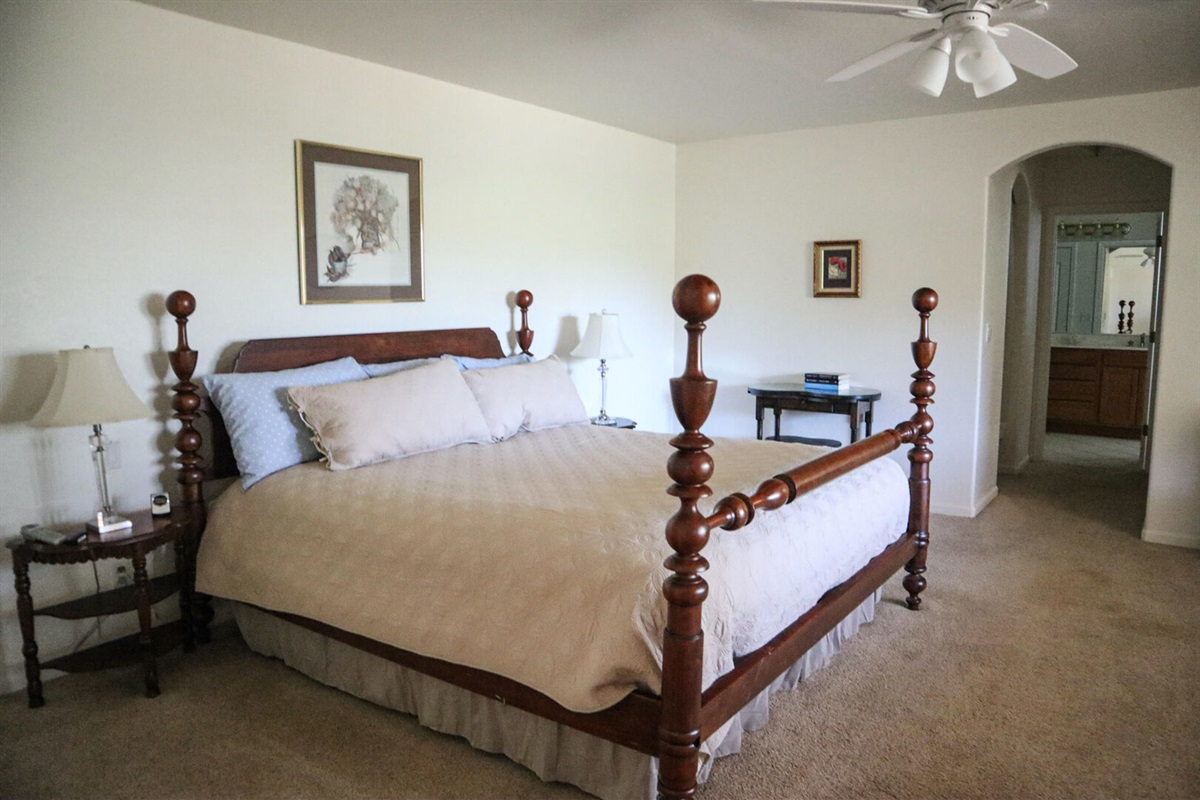 Primary bedroom includes a king size bed with a ceiling fan.