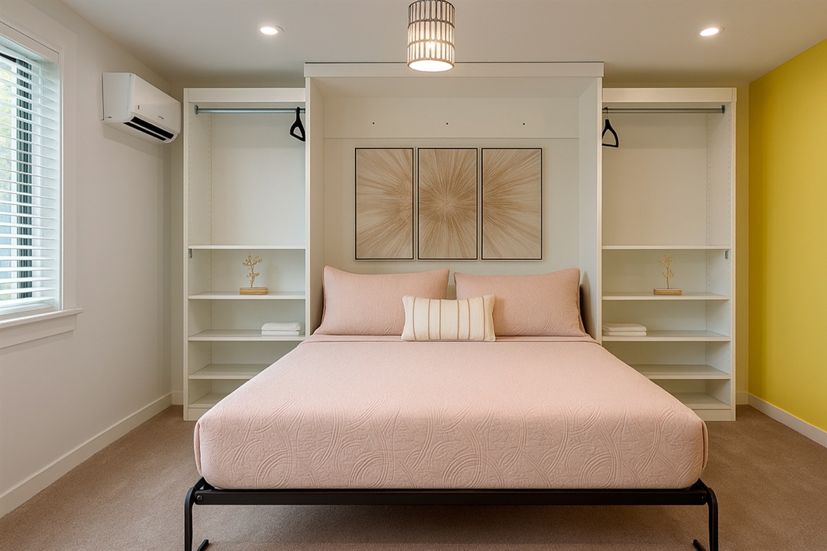 Wide view of The Gold Room at Garden of Manors, showing the bright bedroom, storage, mini-fridge, and sunny accent wall in Wilton Manors.