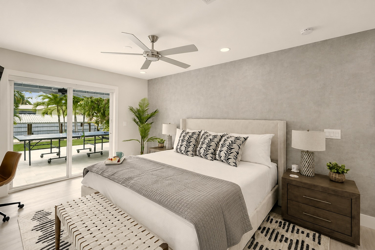 Step from this king bedroom toward the patio, with soft lighting, a desk chair, and the ping-pong area just outside.