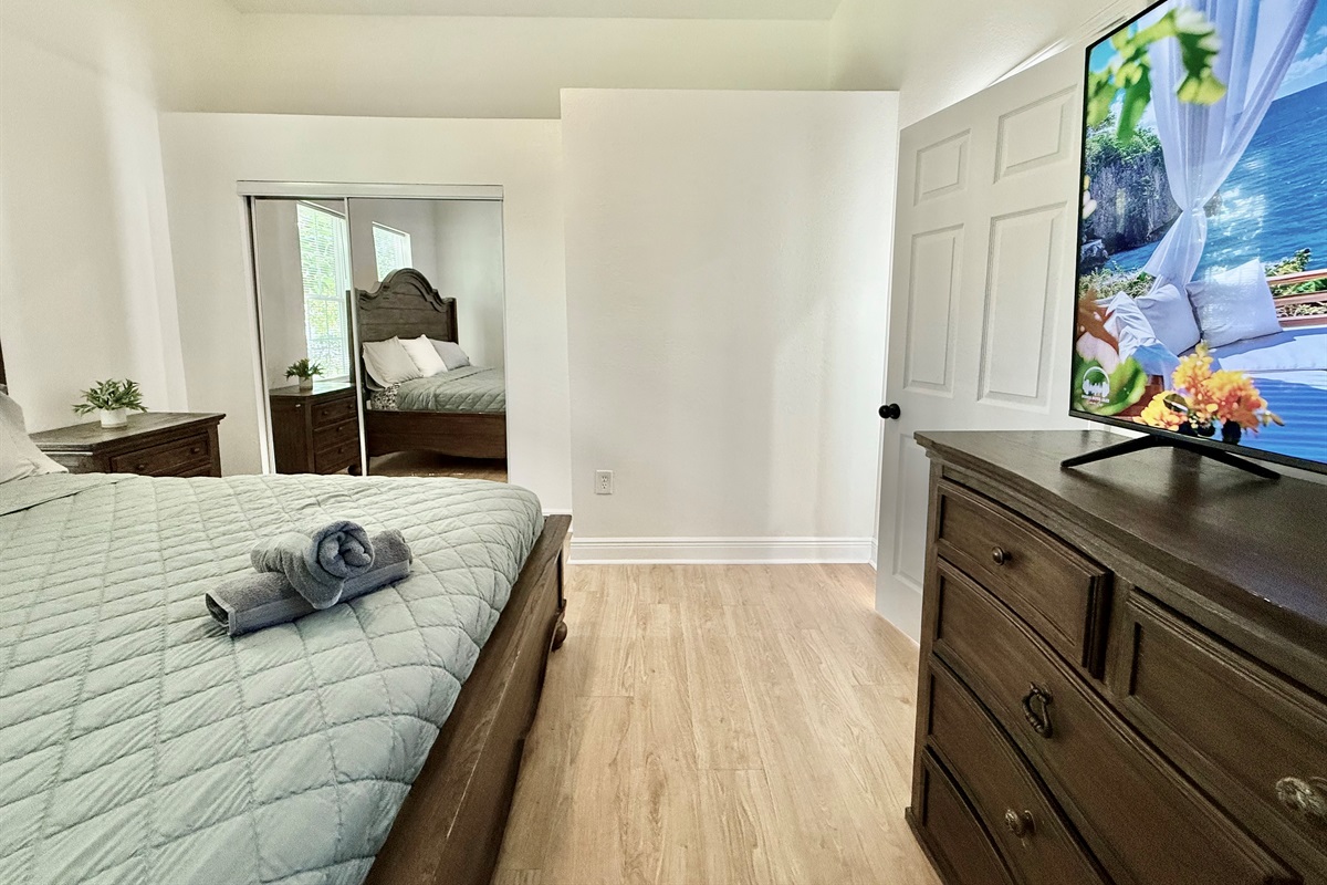 Unwind in timeless style—this spacious bedroom offers a king bed, wood furnishings, and soft lighting for a perfect night’s sleep.