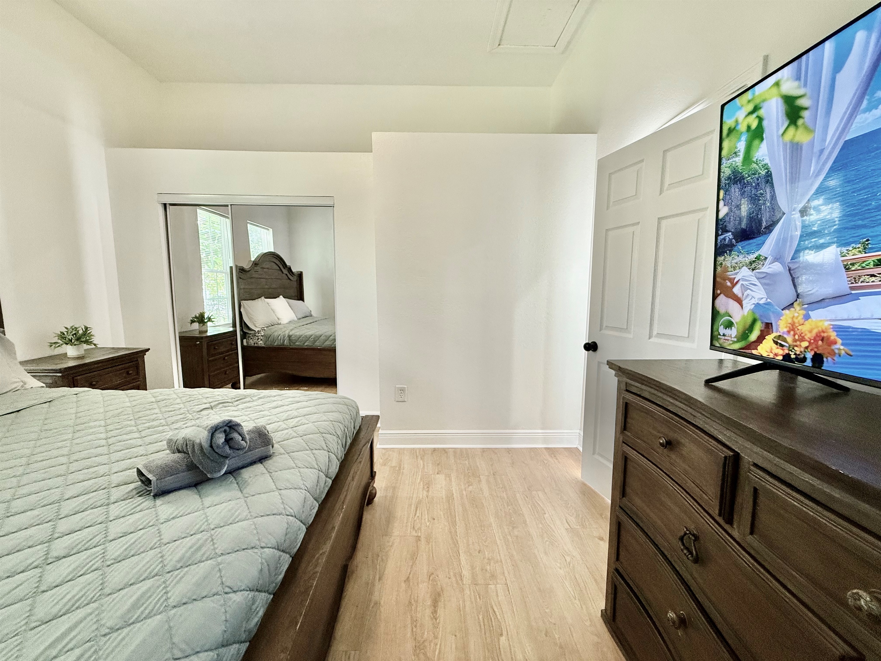 Unwind in timeless style—this spacious bedroom offers a king bed, wood furnishings, and soft lighting for a perfect night’s sleep.