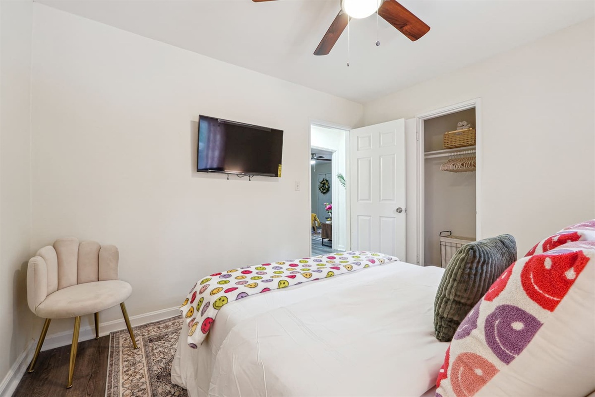 A comfortable bedroom featuring a bed, a ceiling fan, a window, a TV, and a closet — a cozy space to rest and relax.
