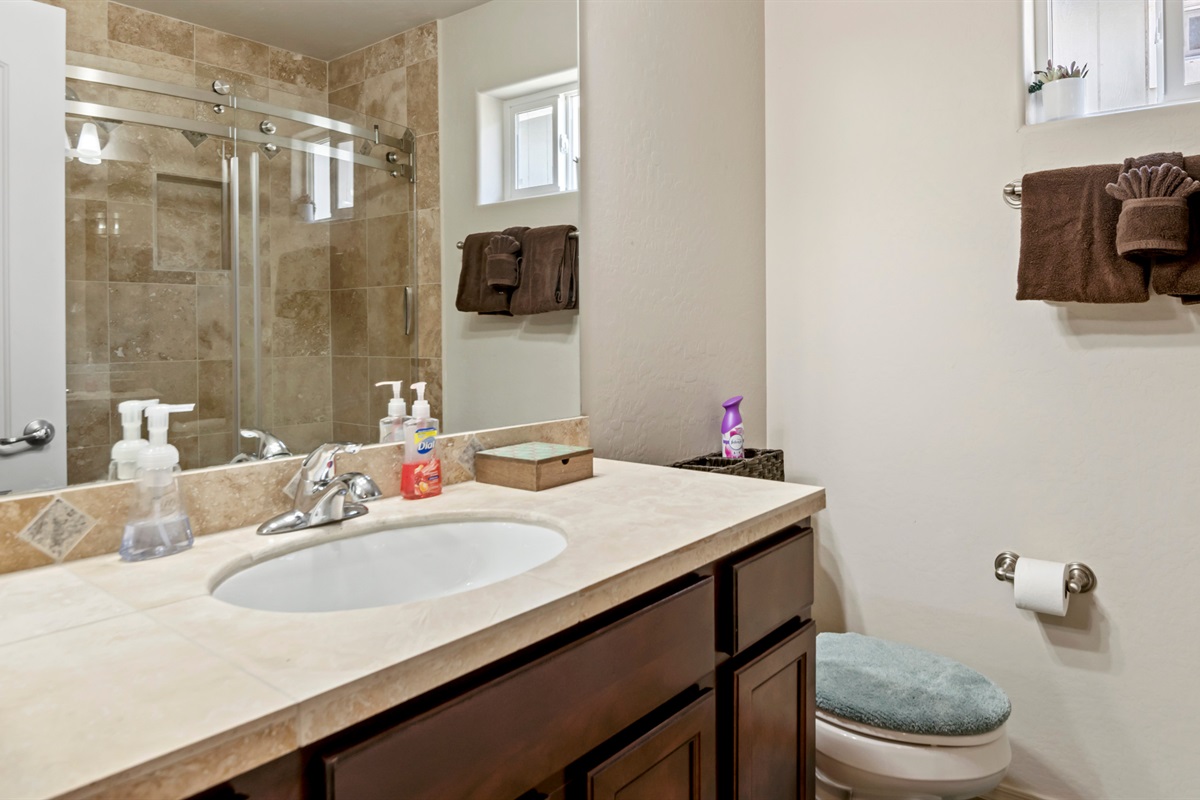 Shared bathroom includes a sleek vanity and toilet, designed for ease and comfort.