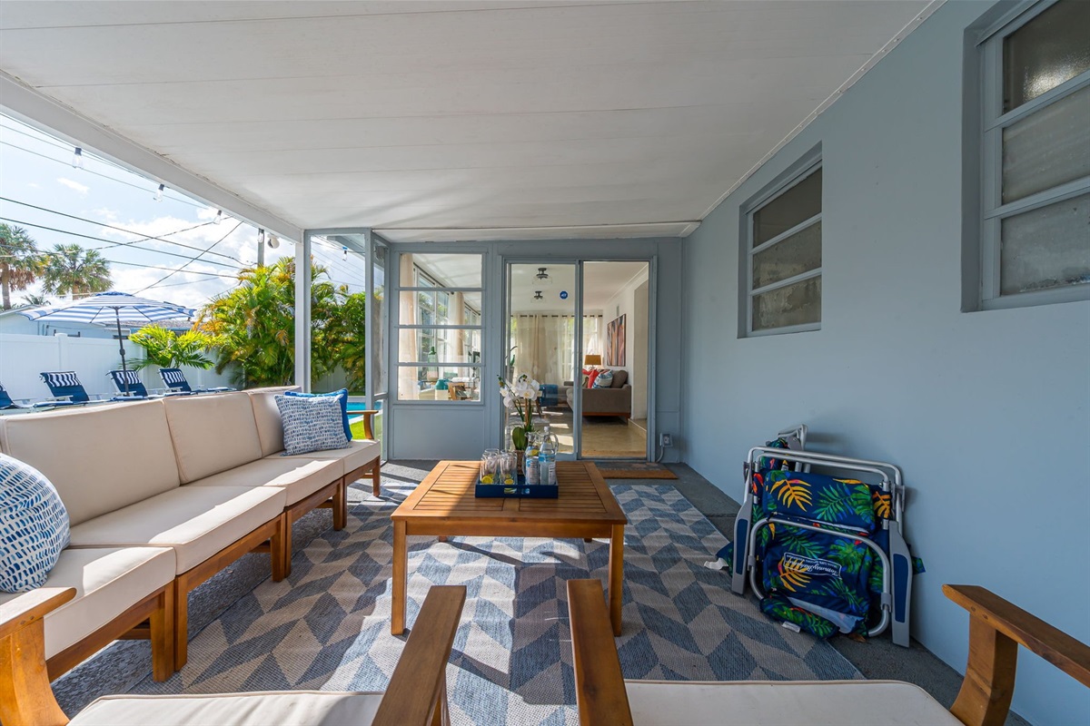 A serene covered patio with chic seating, alfresco dining, a gas grill, and a two-person hammock, all framed by a mix of manicured turf and lush lawn—your private outdoor retreat.