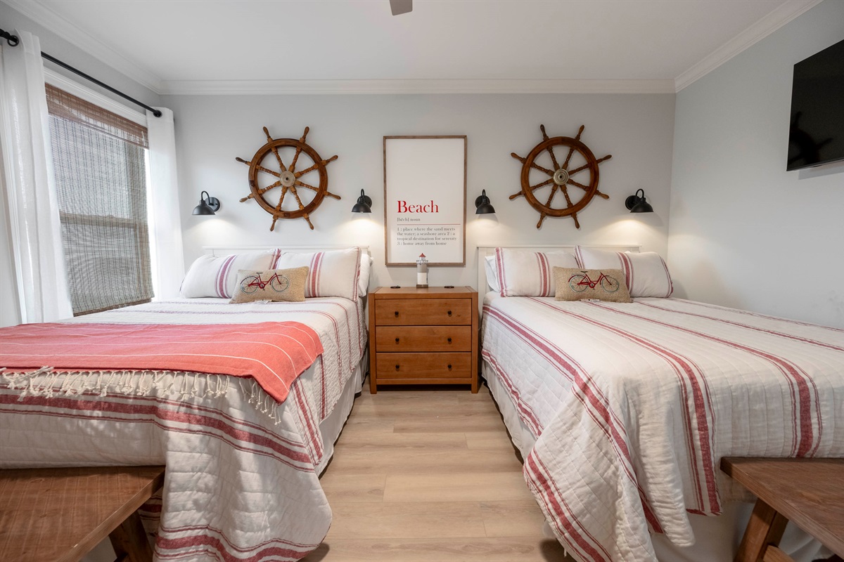 Nautical charm: Cozy bedroom with twin beds, ship wheel decor, and beach vibes.