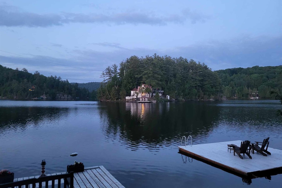 As night falls over the lake,  cottage lights come on; the view is quite beautiful