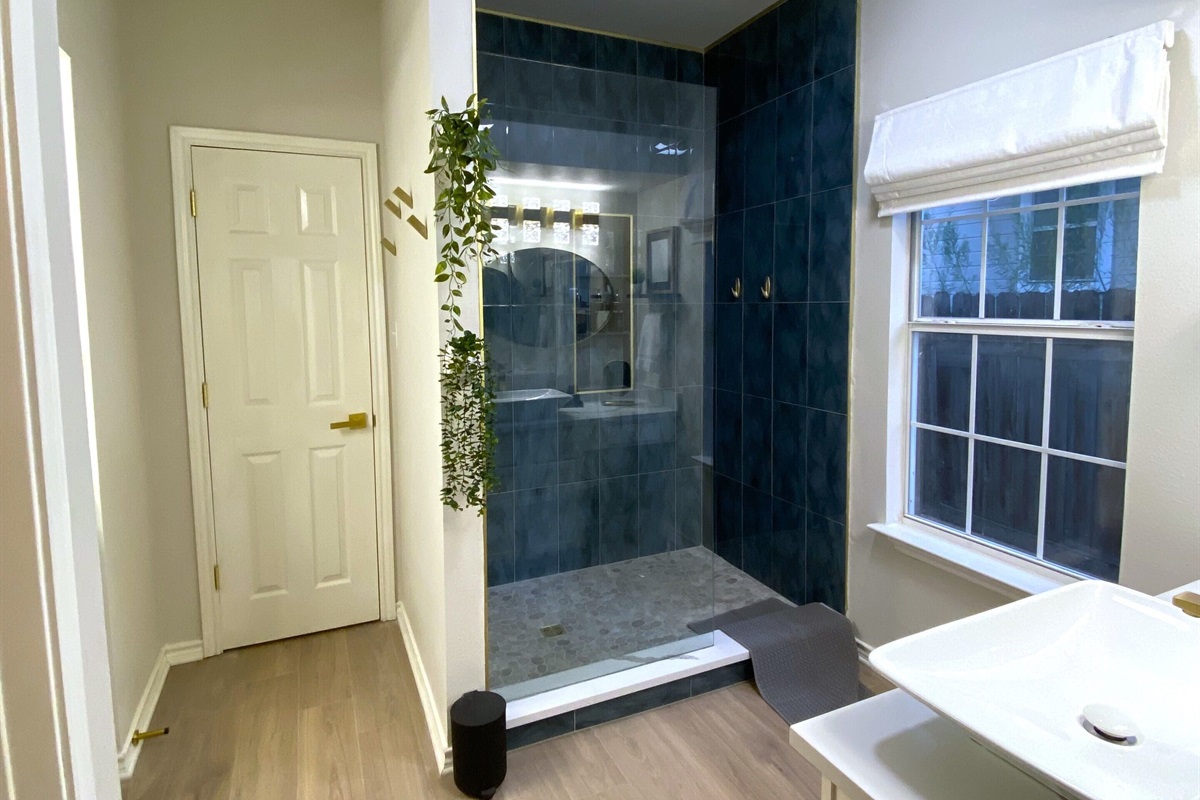 Indulge in luxury in this stunning en suite master bathroom! Enjoy the sleek, glass-enclosed shower with gorgeous blue tiles and gold accents, plus complimentary shampoo, conditioner, and shower gel. Your private oasis awaits—pamper yourself!