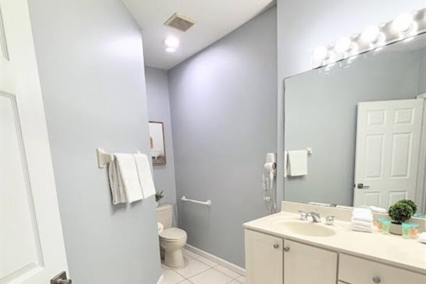 Clean and bright bathroom featuring a spacious vanity, large mirror, tile flooring, and neutral finishes.