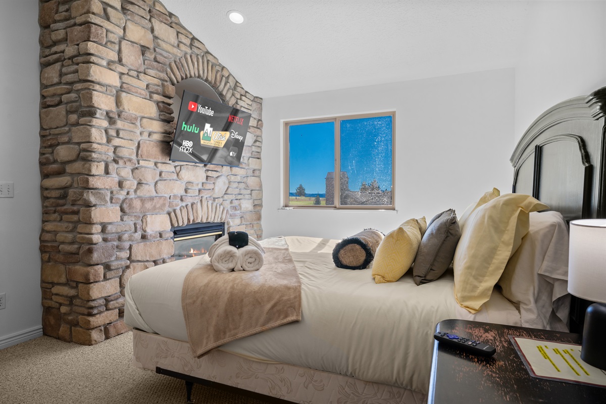 Warm and relaxing bedroom with a stone fireplace and TV — perfect for unwinding after a day on the slopes.