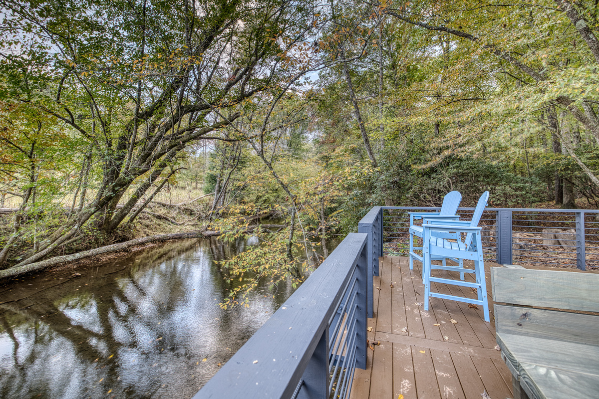 Deck over the creek with blue chairs.