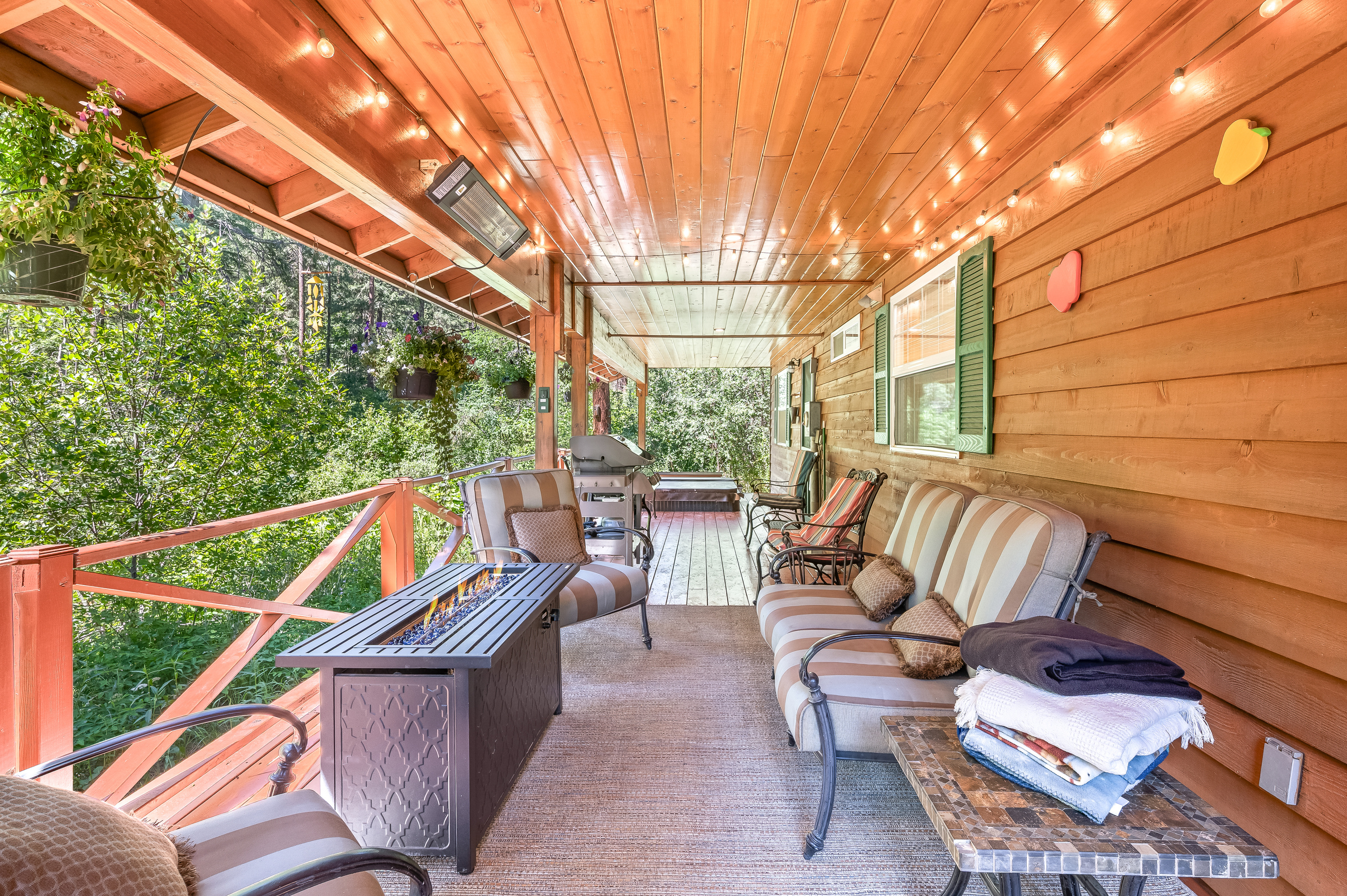 Large covered back porch includes seating, fire table, outdoor heater, BBQ and hot tub