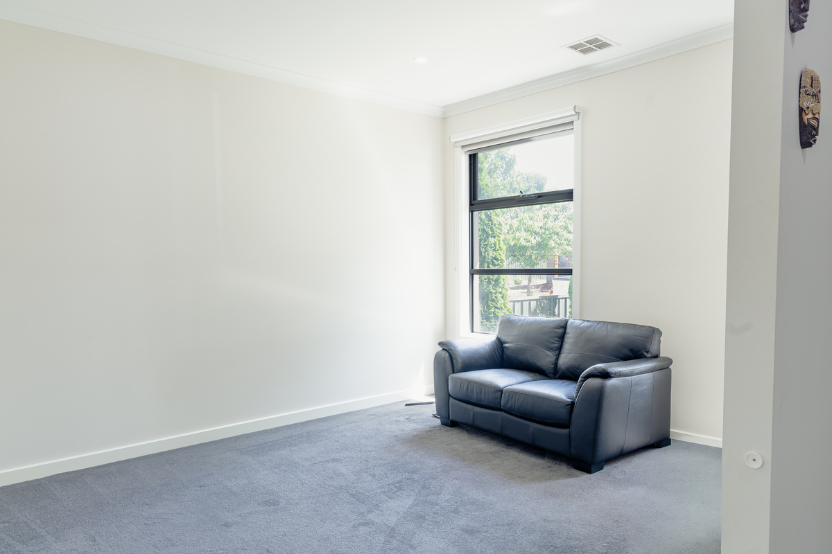 Second living area with wall-mounted TV and carpeted flooring.