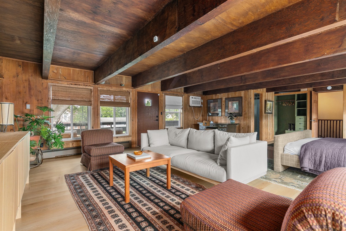 Large windows brighten the room with natural light, while a private door leads directly to the outdoor lounge deck — perfect for stepping out with your morning coffee or winding down in the evening air.
