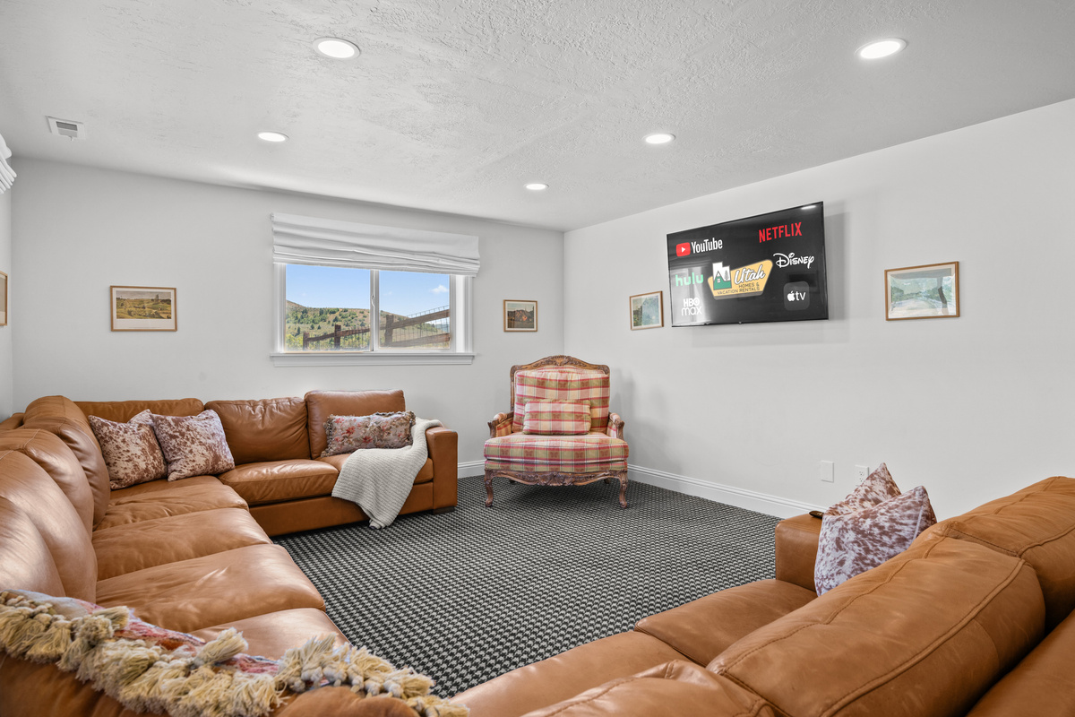 Settle in for movie nights or quiet evenings in this spacious Lower Level room, complete with extensive seating and a wall-mounted smart television.