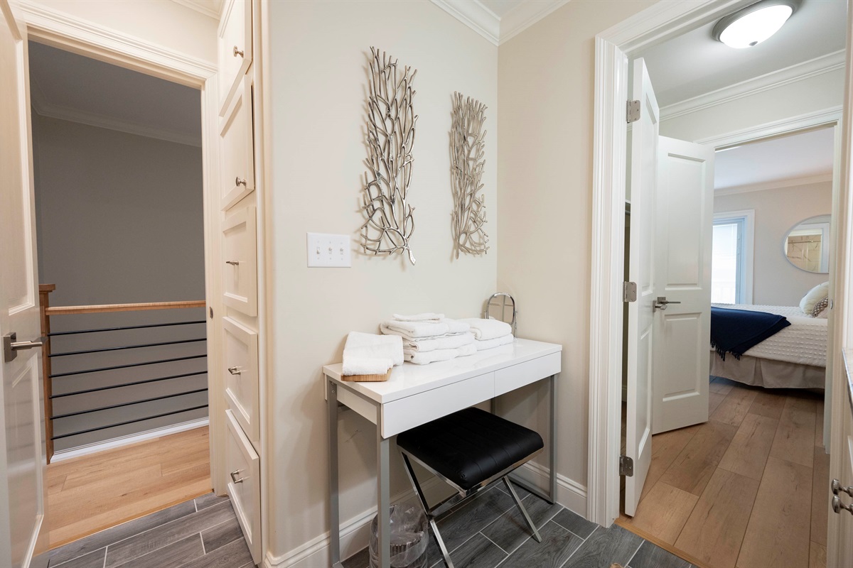 A sleek makeup vanity tucked in the corner of a bathroom hallway, offers a practical and stylish space for freshening up.
