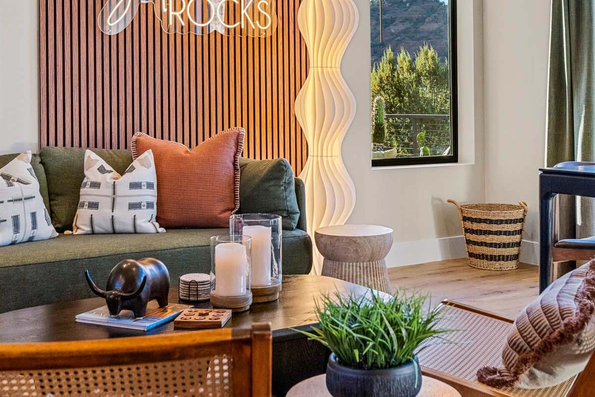 Layered textures, soft lighting, and thoughtful decor create a comfortable living space, with views of Sedona's Pyramid Rock visible just beyond the windows.