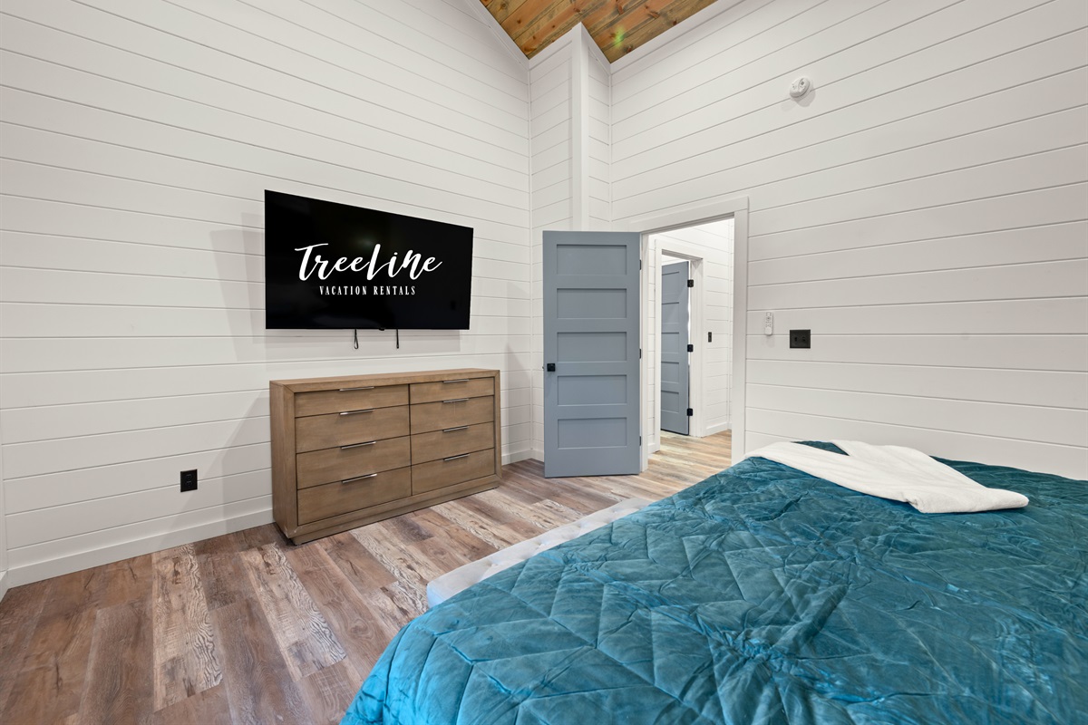 Natural light pours into this inviting king bedroom, highlighting the cozy bedding and warm finishes that make the space feel