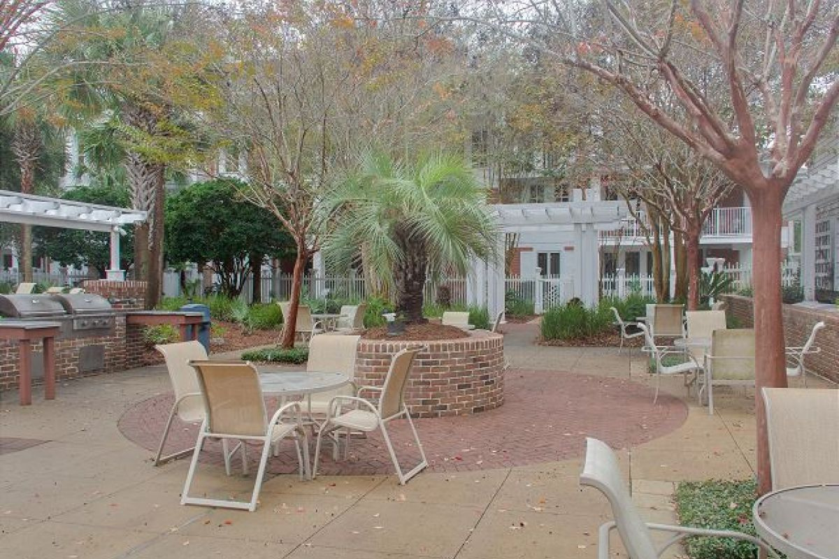 Pilot House courtyard patio with tables, grills and pergola shaded by trees